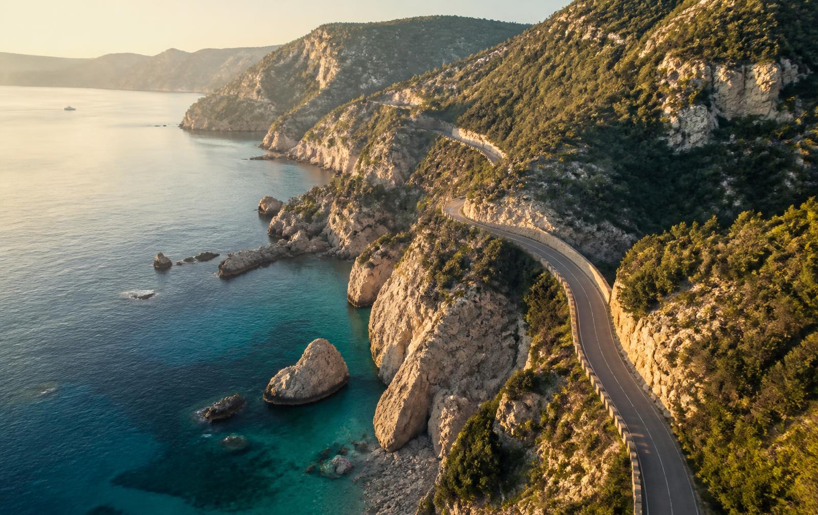 Coastal road winding along Mediterranean cliffs at golden hour
